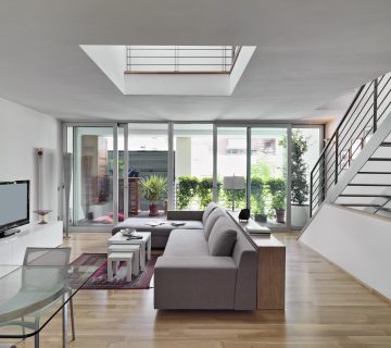 interior view of a modern living room with fabric sofa overlloking on the terrace and staircase